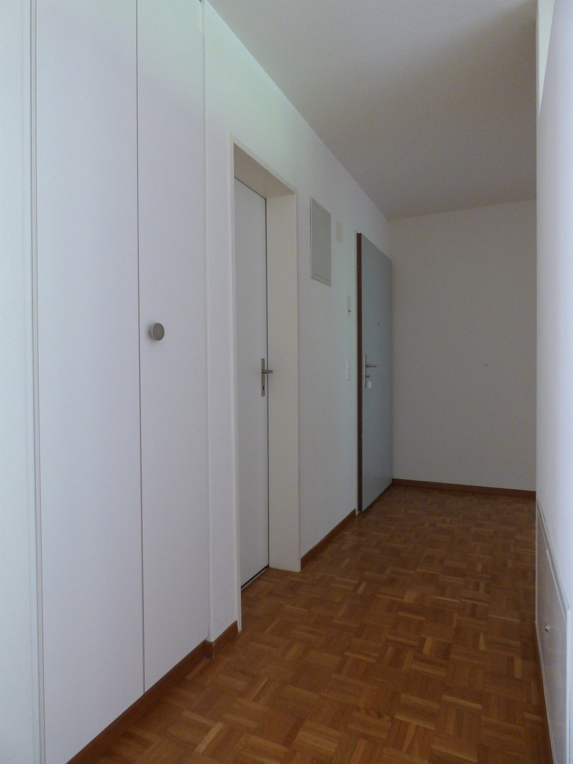 Heller Flur mit Holzparkett und weißen Wänden