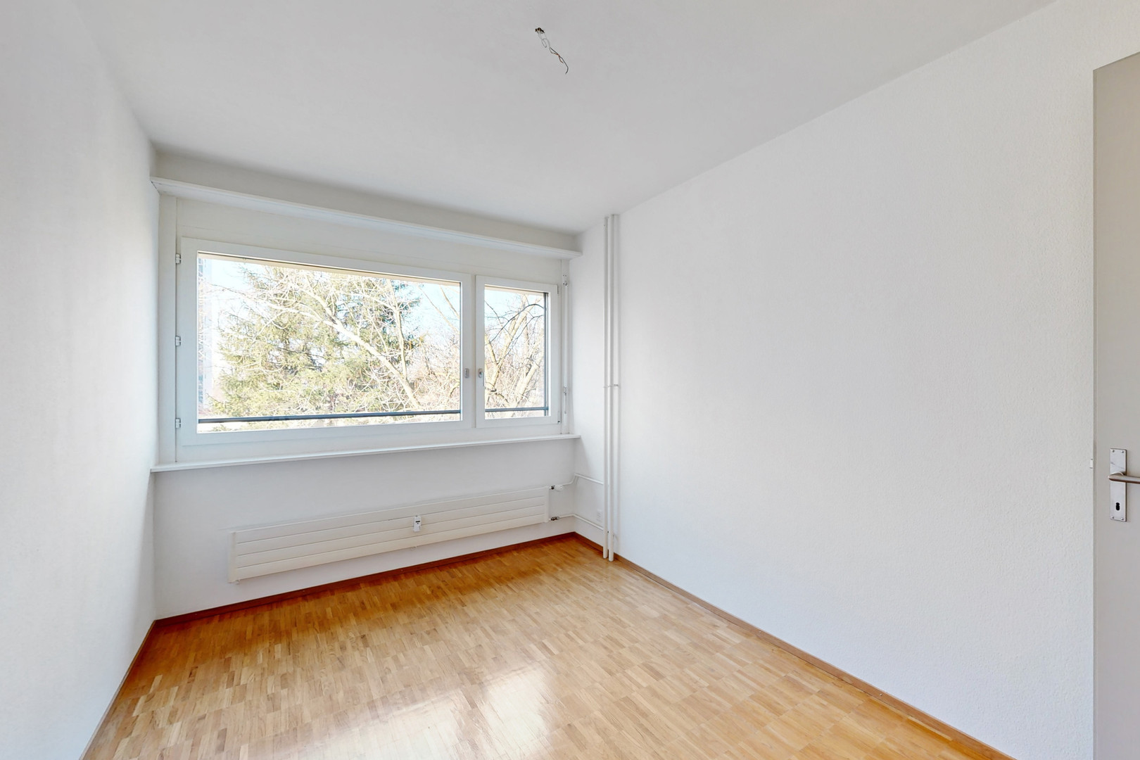 Helles, leerstehendes Zimmer mit Fenster und Holzfußboden