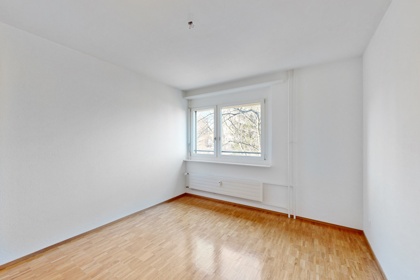 Helles, leeres Zimmer mit Fenster und Heizkörper