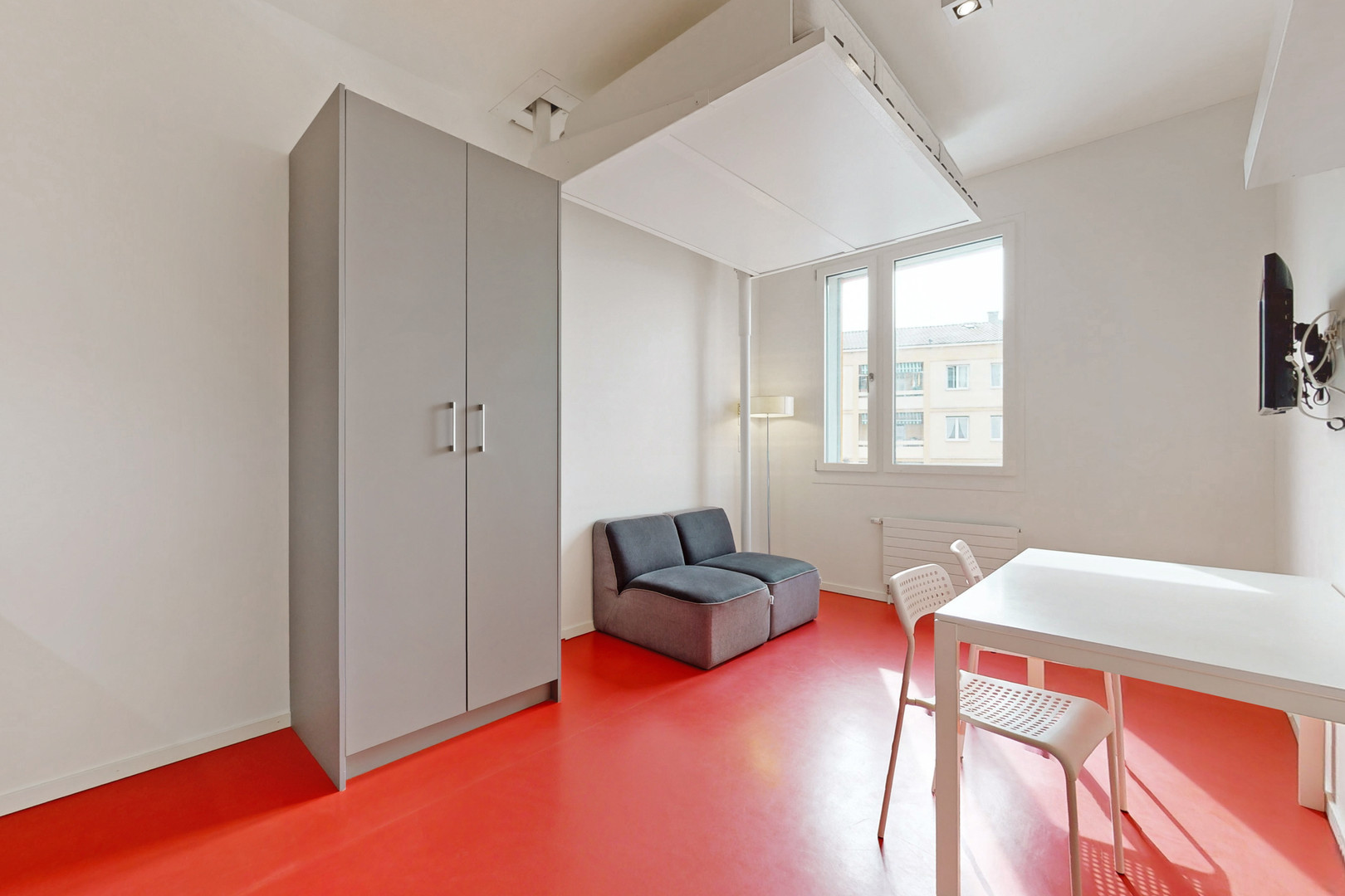 Helles Zimmer mit rotem Boden und großer Fensterfront