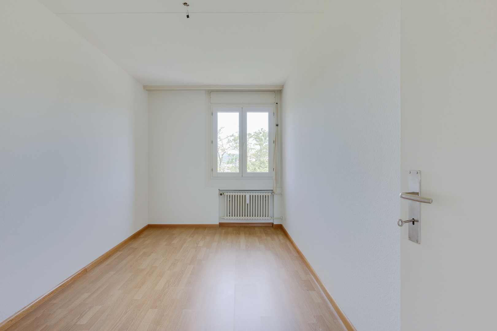 Leerer heller Raum mit Fenster und Heizkörper