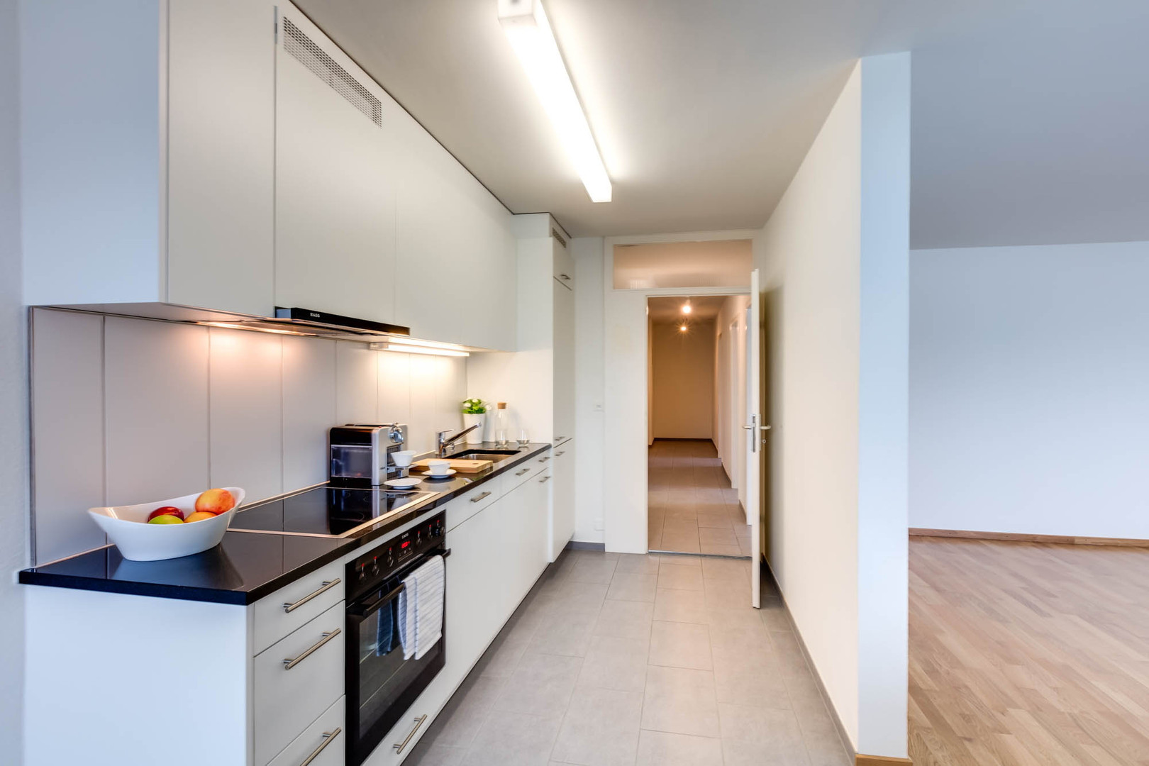Schmale, moderne Einbauküche mit Fluransicht