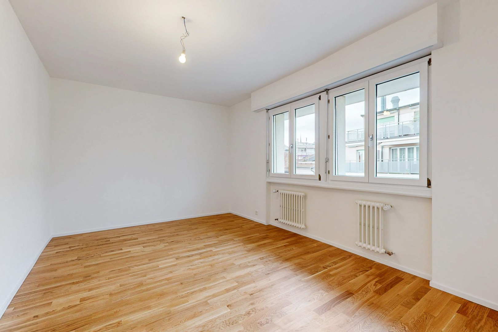 Leerer Wohnraum mit Parkett und Fenstern