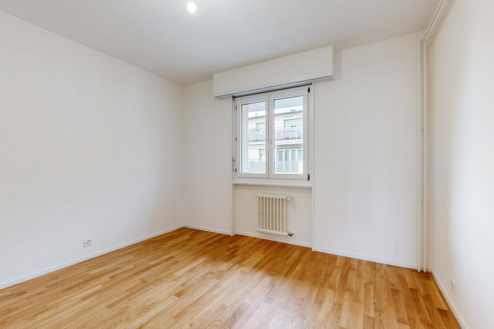 Heller leerer Wohnraum mit Parkett und Fenster