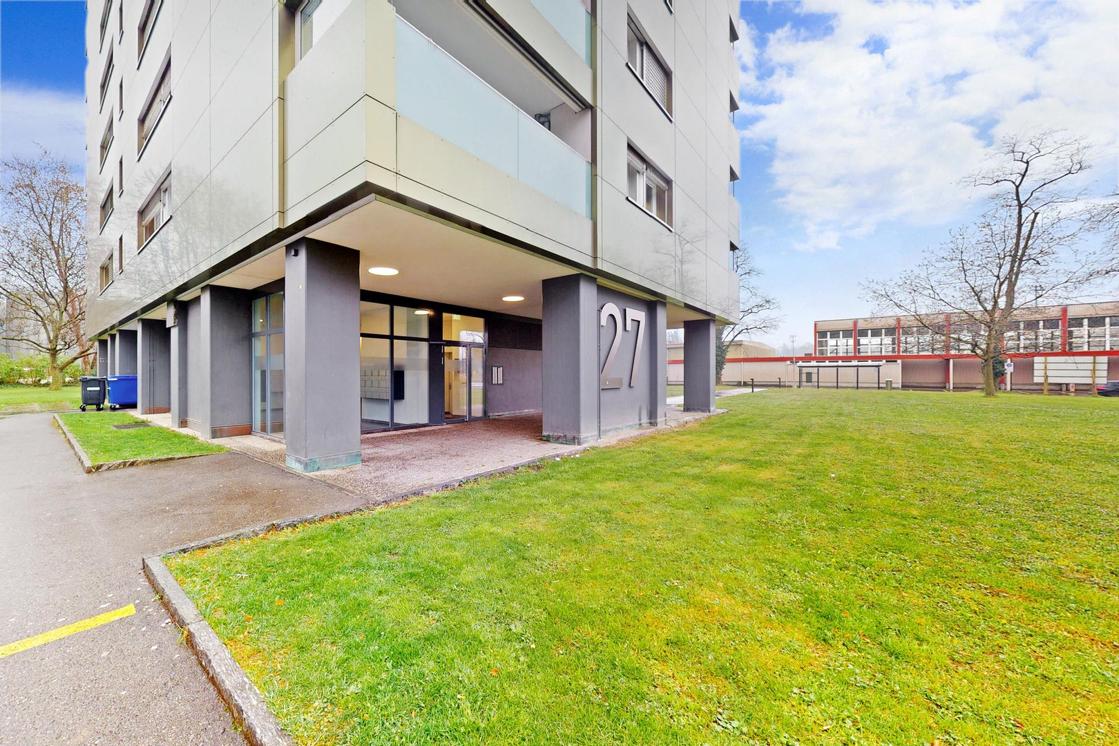 Modernes Mehrfamilienhaus mit Eingang und Grünfläche