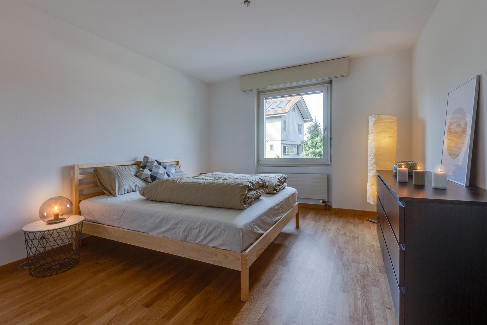 Helles Schlafzimmer mit Holzbett und Fensterblick