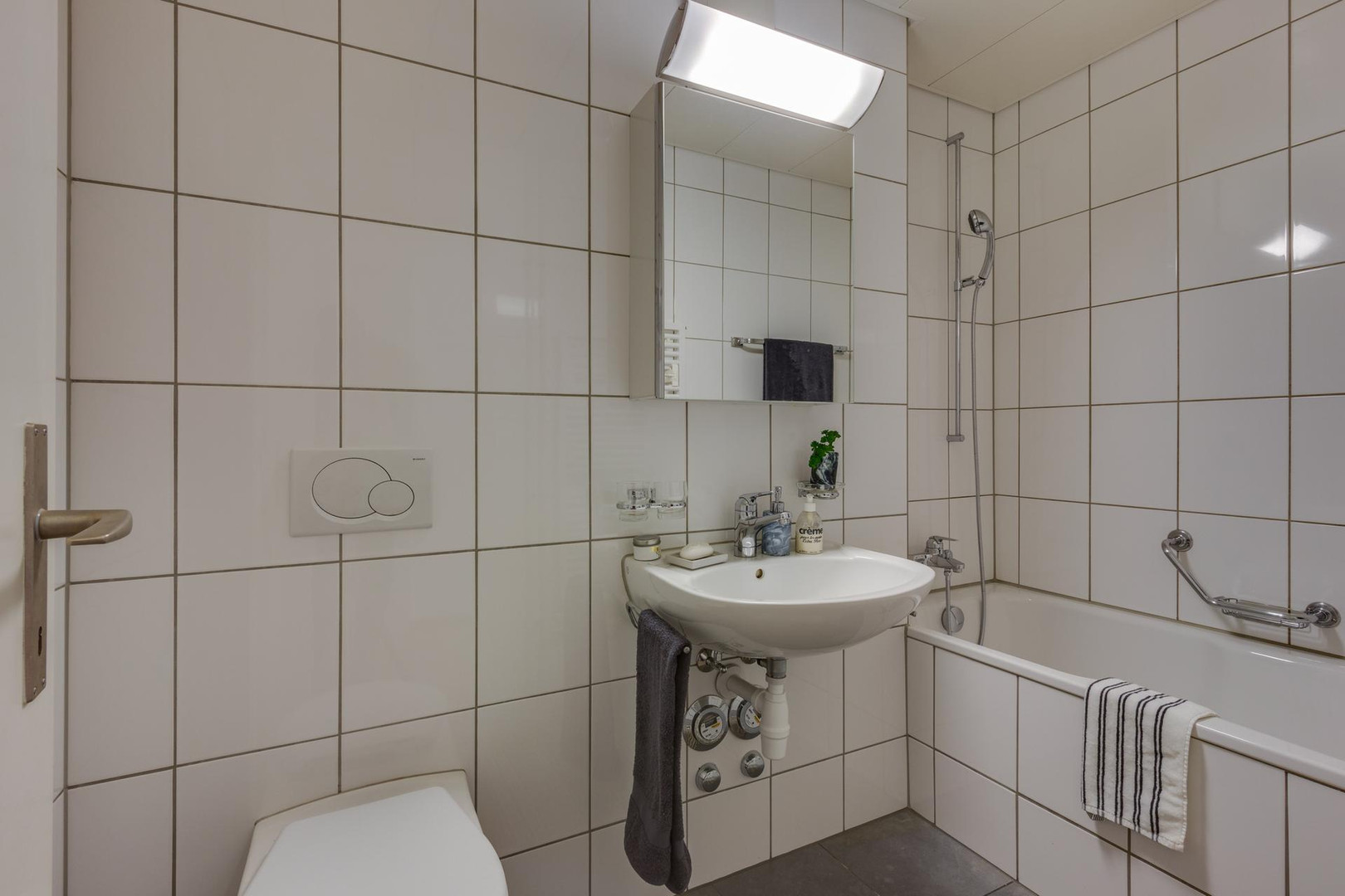 Kleines Badezimmer mit Badewanne und Wandfliesen