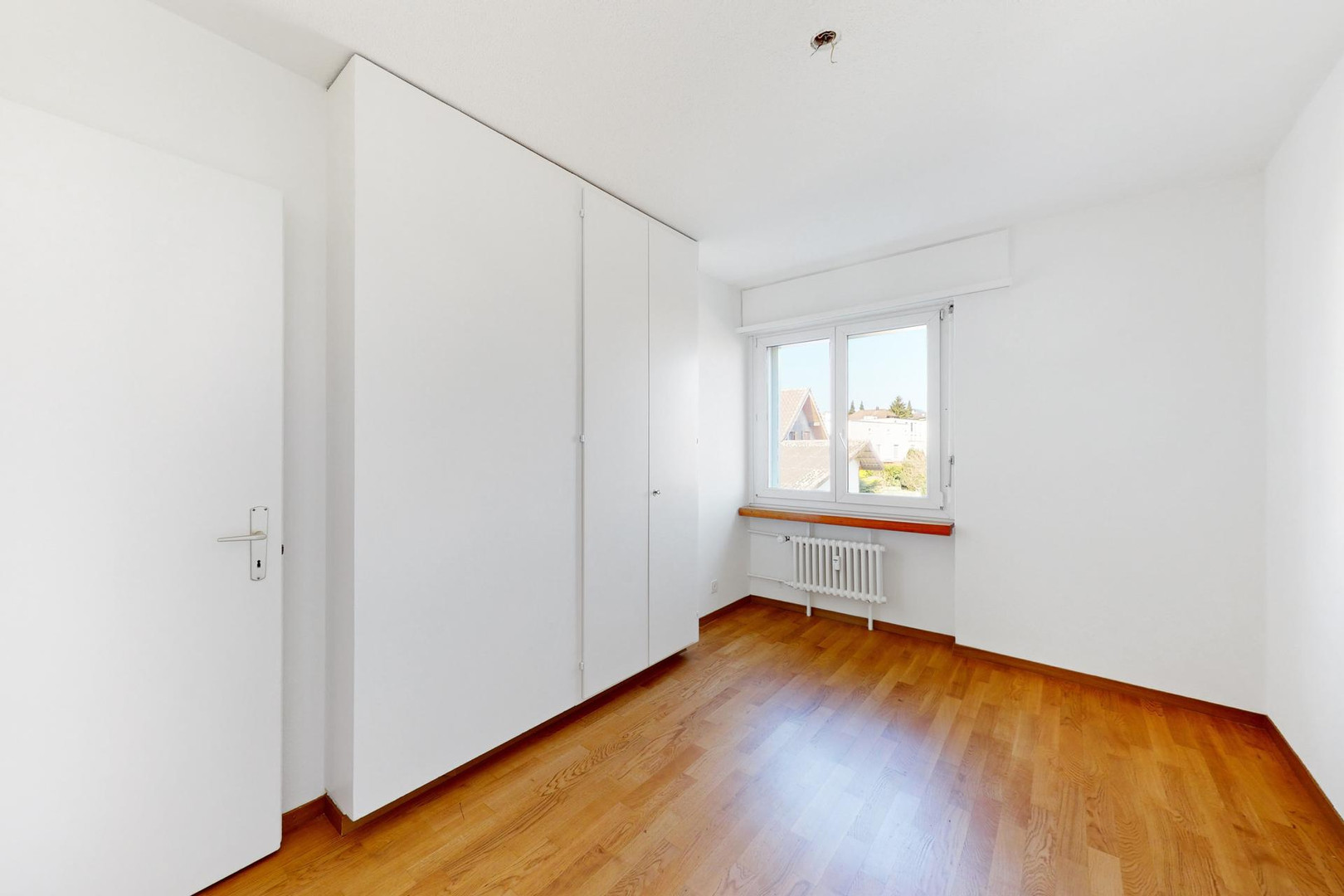 Helles, leeres Zimmer mit Einbauschrank und Fenster