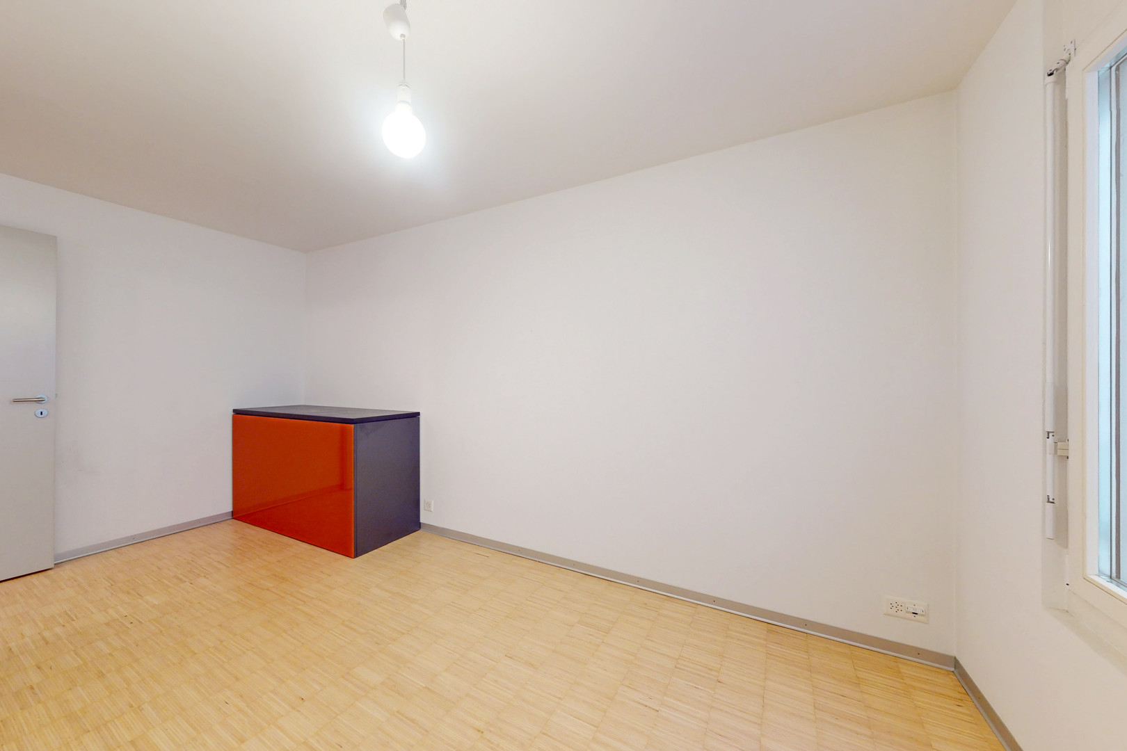 Leerer heller Raum mit heller Holzoptik und farbigem Unterschrank