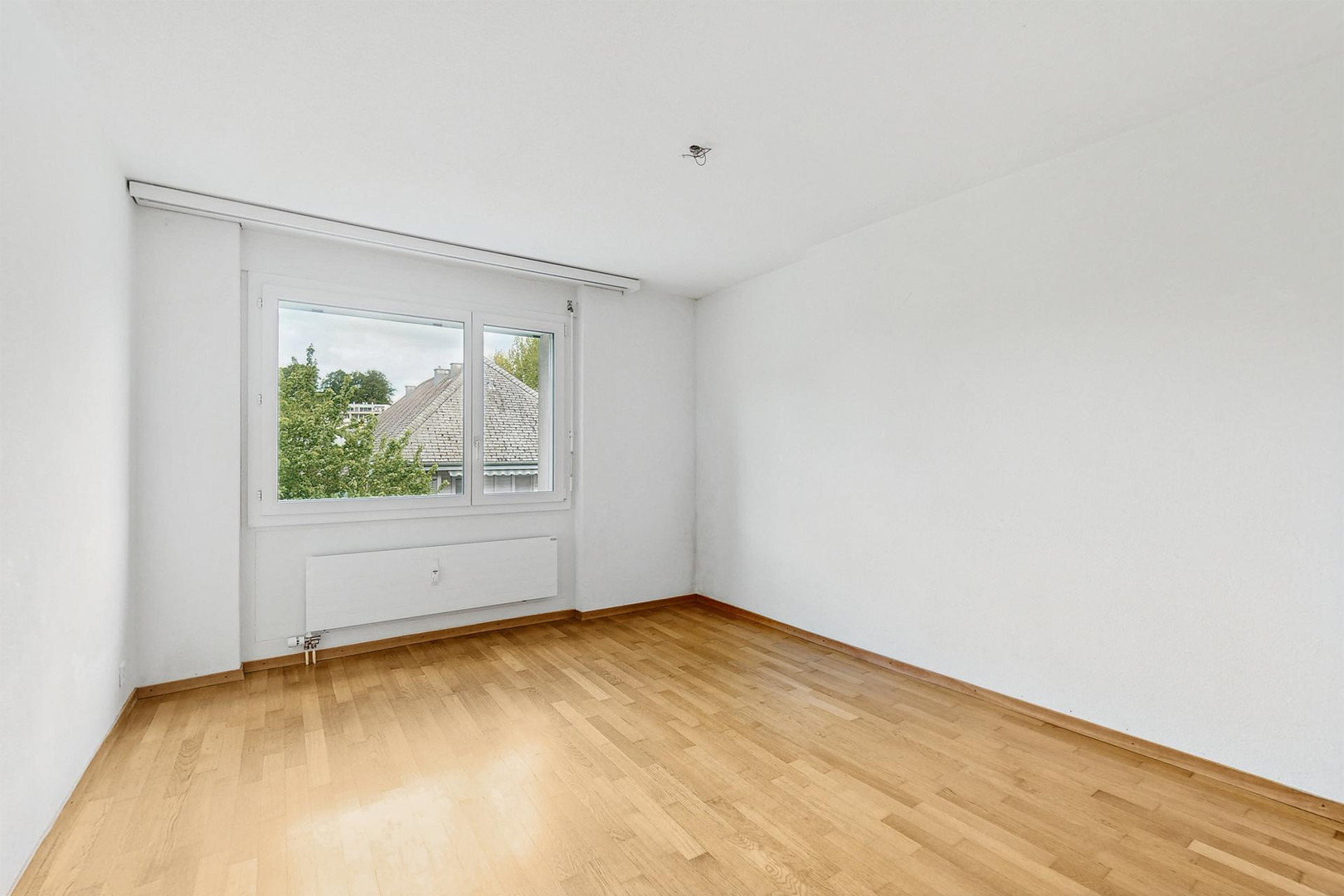 Leerer heller Raum mit Parkett und Fenster