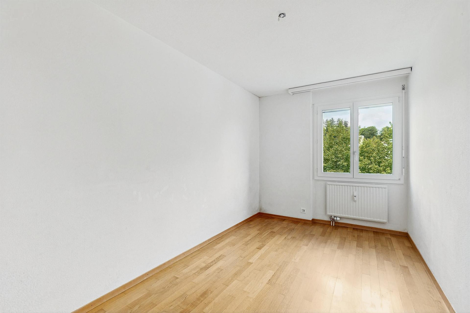Leerer heller Raum mit Fenster und Heizkörper