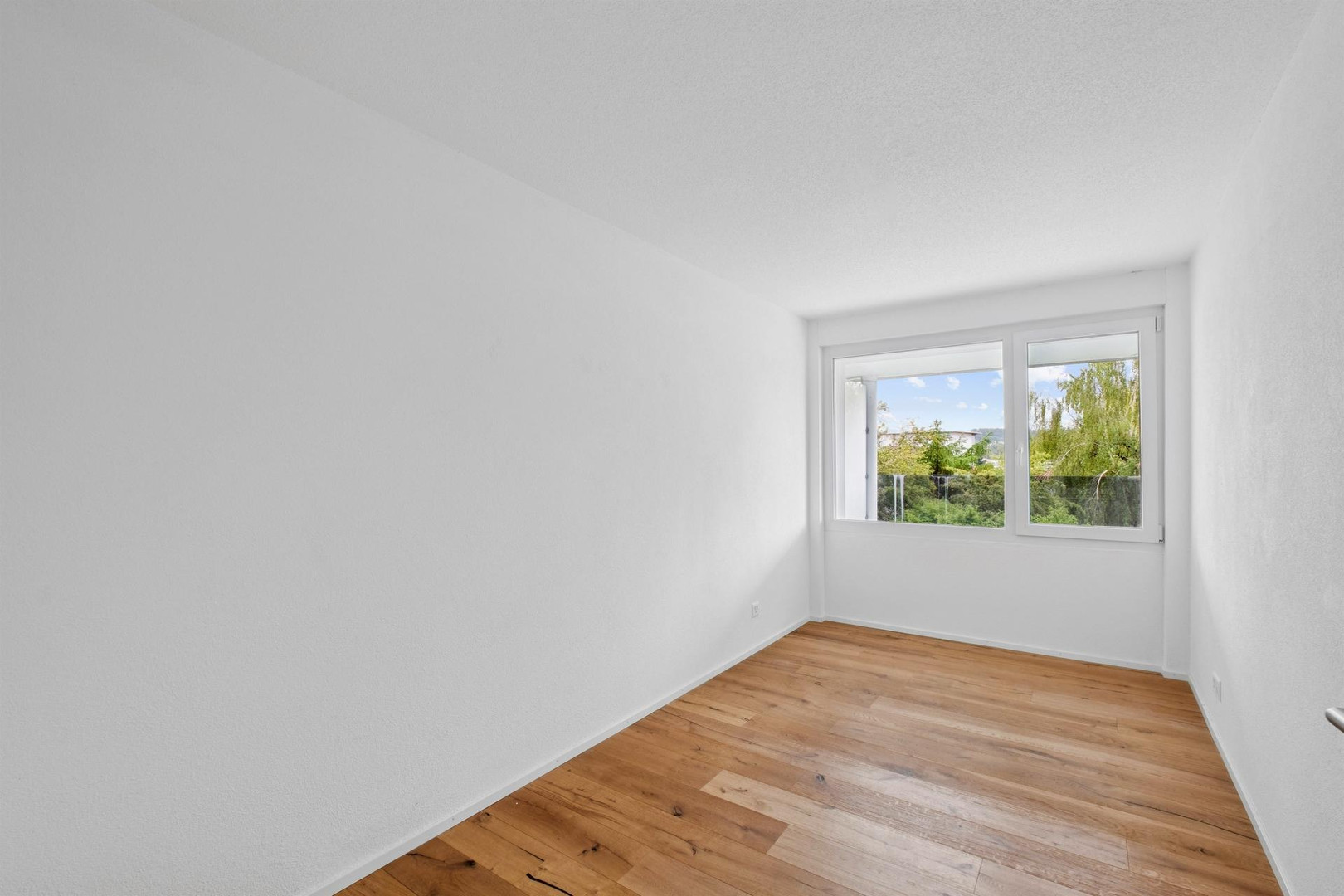 Helles leeres Zimmer mit Fensterblick ins Grüne