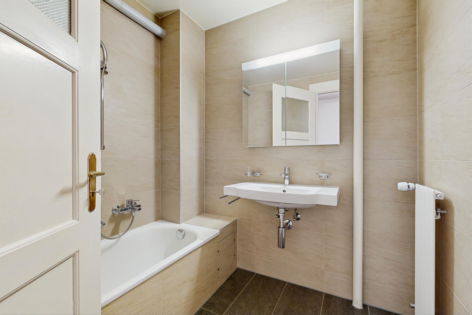 Kleines helles Badezimmer mit Badewanne und Waschtisch