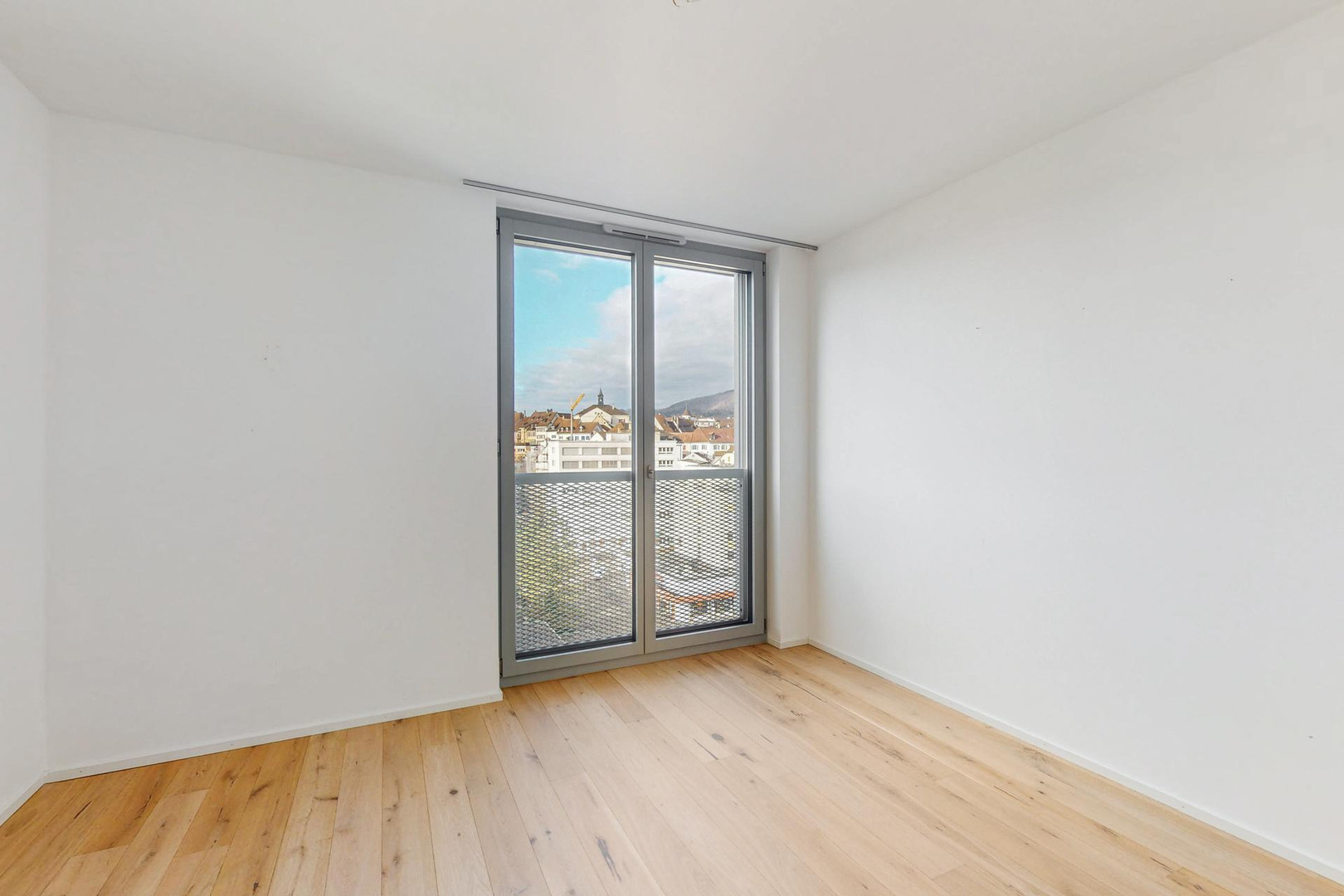 Heller, leerer Raum mit Balkon- oder Terrassentür und Stadtblick