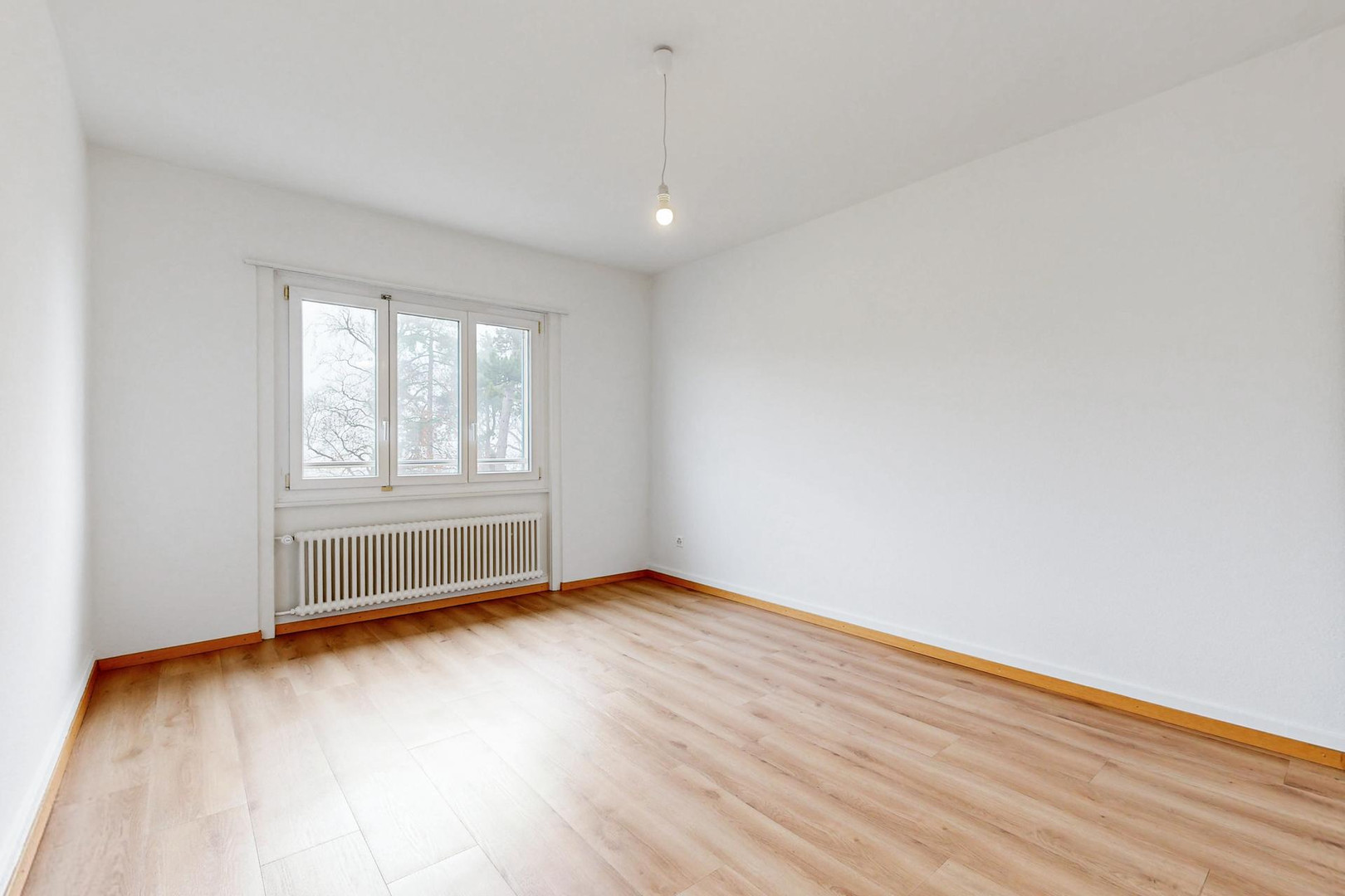 Helles, leeres Zimmer mit Fenster und Heizkörper