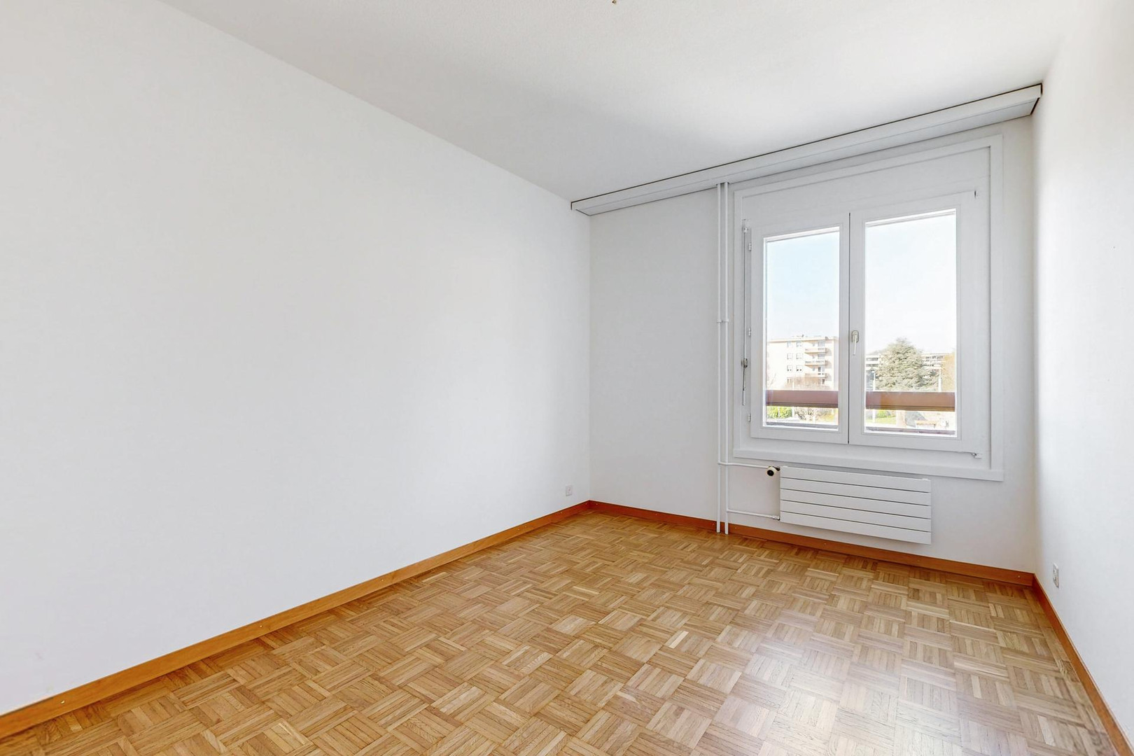 Heller leerer Raum mit Parkettboden und Fenster