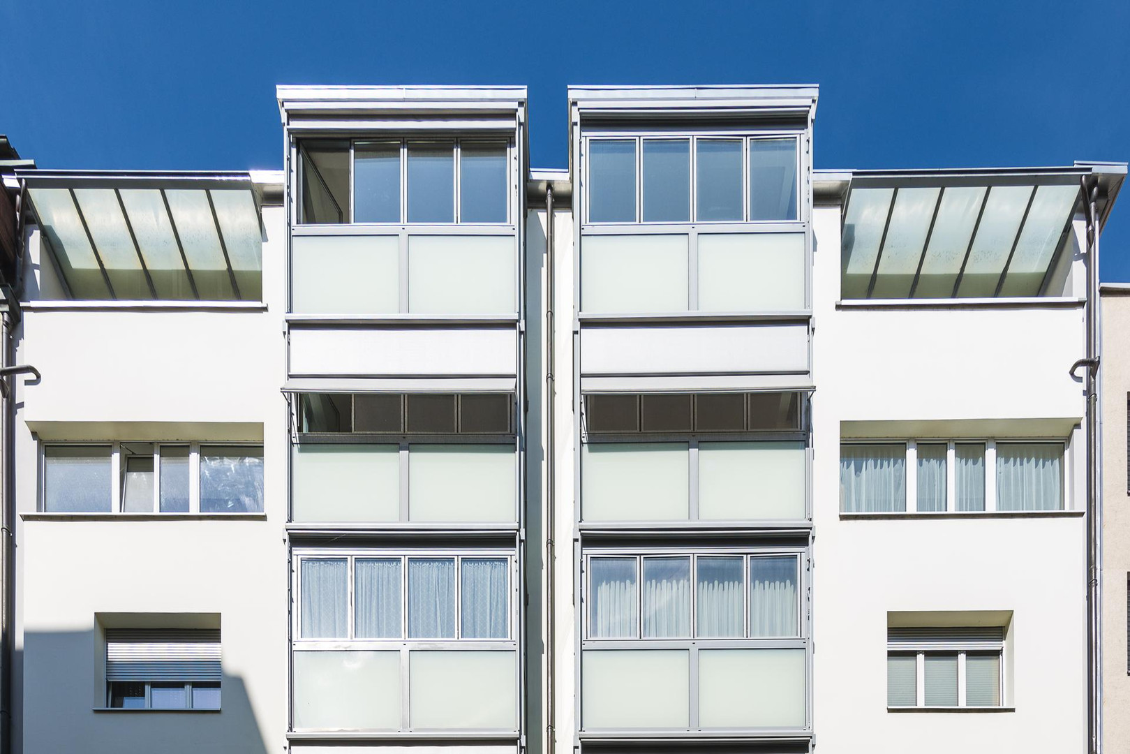 Moderne weiße Fassade mit großen Fensterfronten