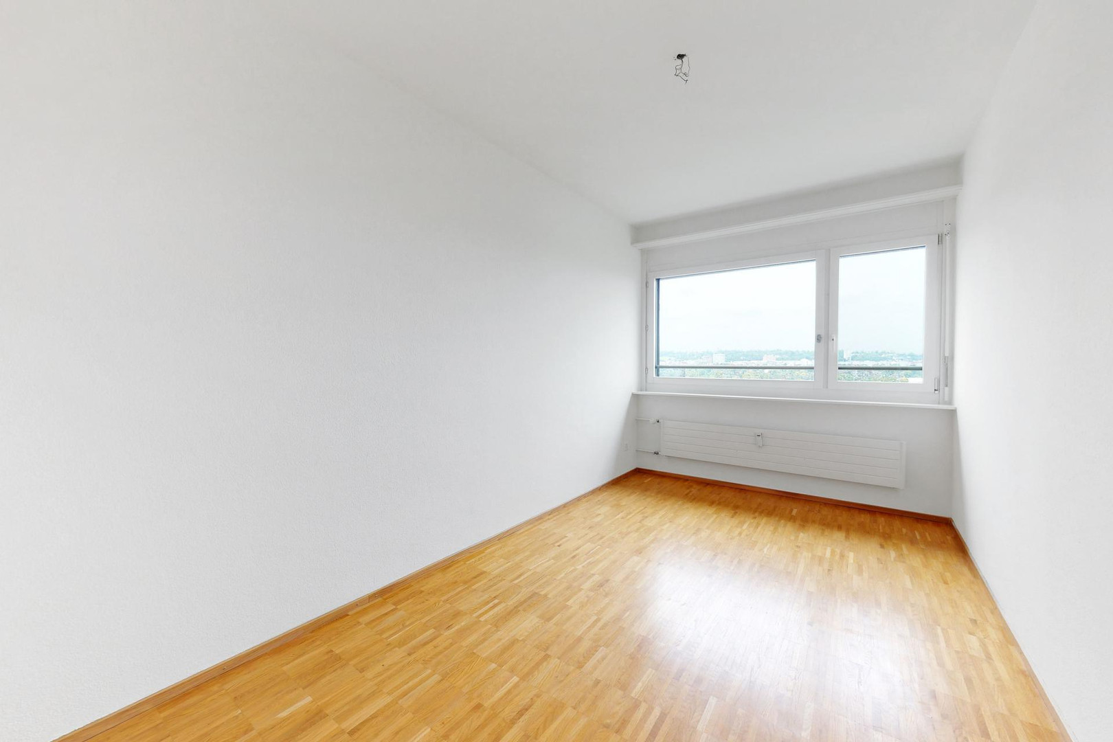 Leerer heller Raum mit Holzfußboden und großem Fenster
