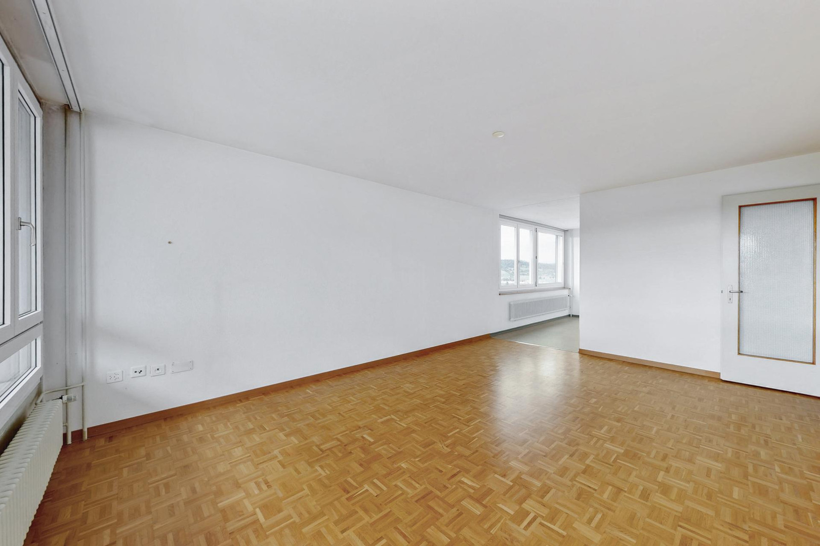 Leerer heller Wohnraum mit Parkettboden