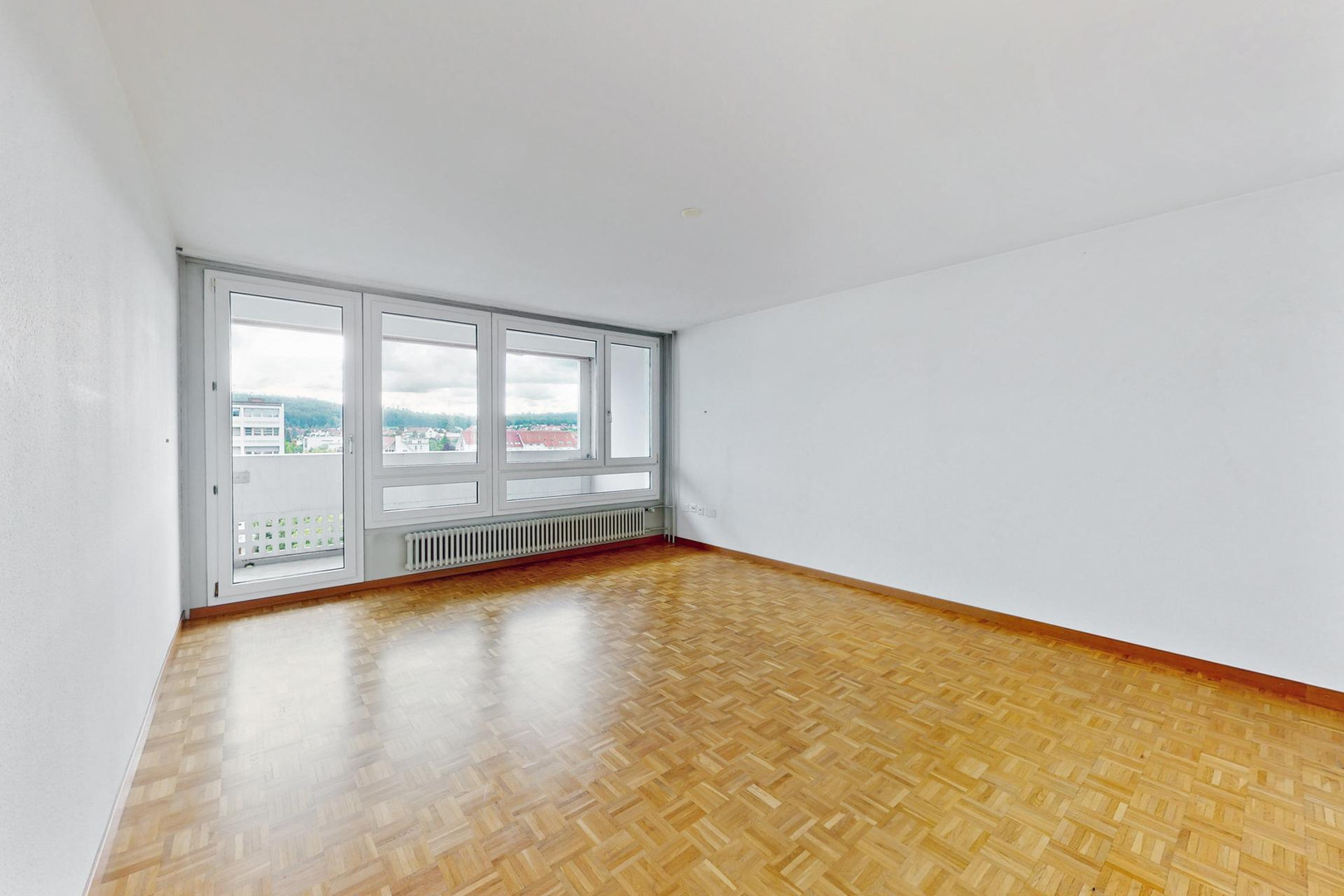 Heller leerer Wohnraum mit Balkon und Parkettboden