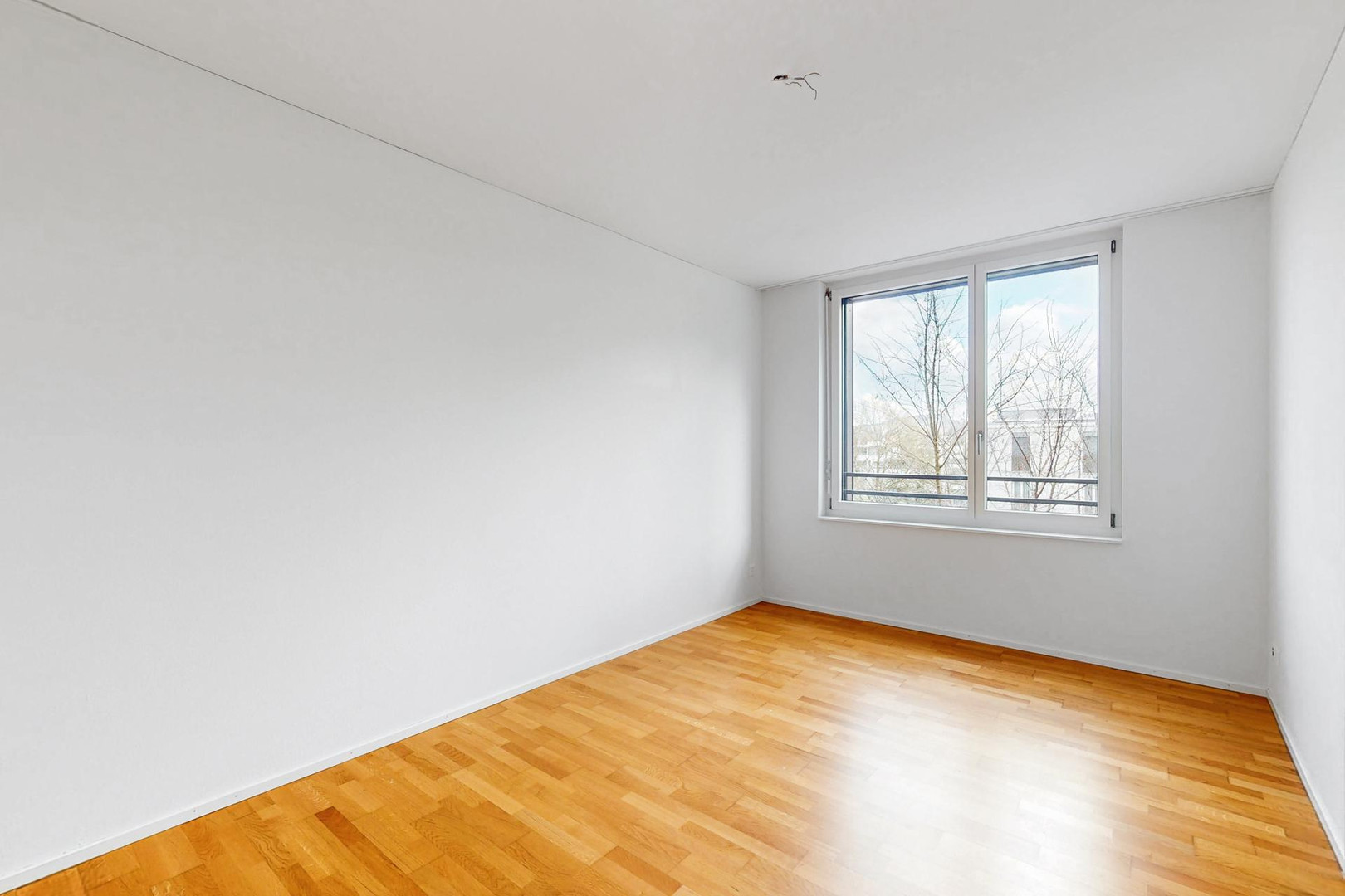 Heller leerer Raum mit Parkett und Fenster