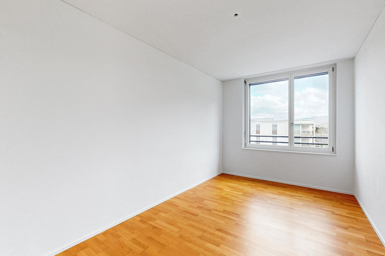 Heller leerer Raum mit Parkett und Fenster