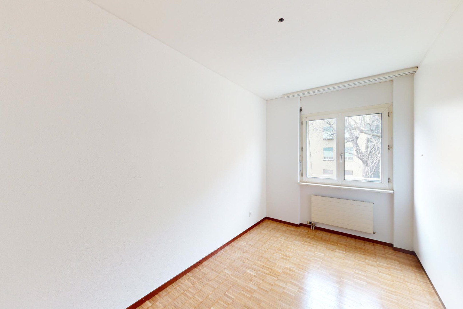 Leerer, heller Raum mit Fenster und Heizkörper