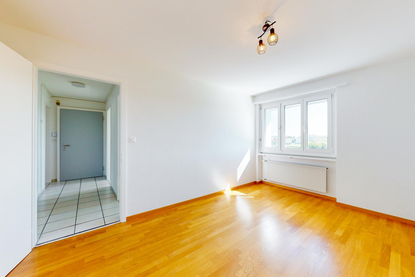 Helles, leerstehendes Zimmer mit Parkettboden und Fensterblick