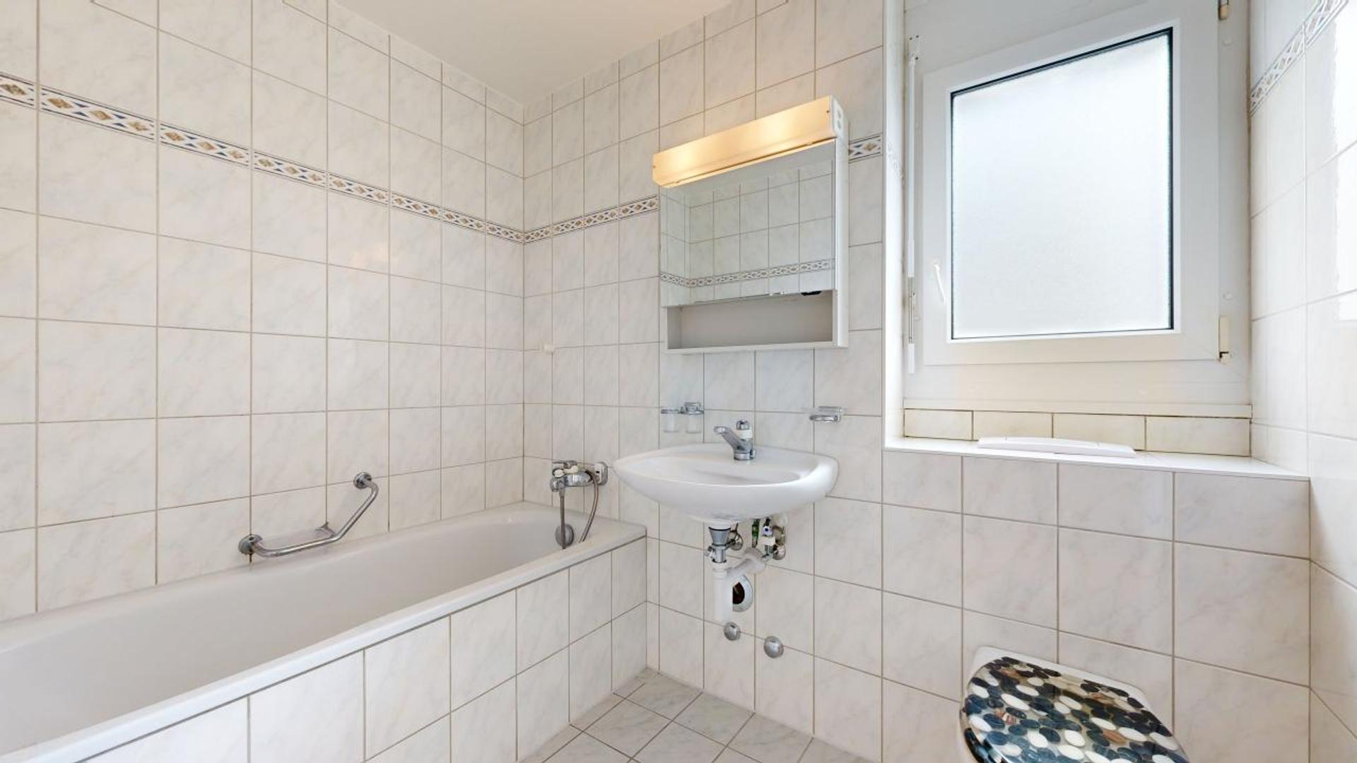 Helles Badezimmer mit Badewanne und Fenster