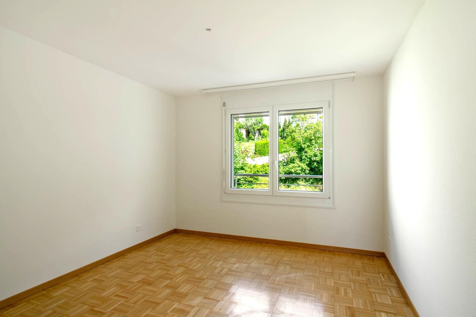 Helles, leeres Zimmer mit Fensterblick ins Grüne