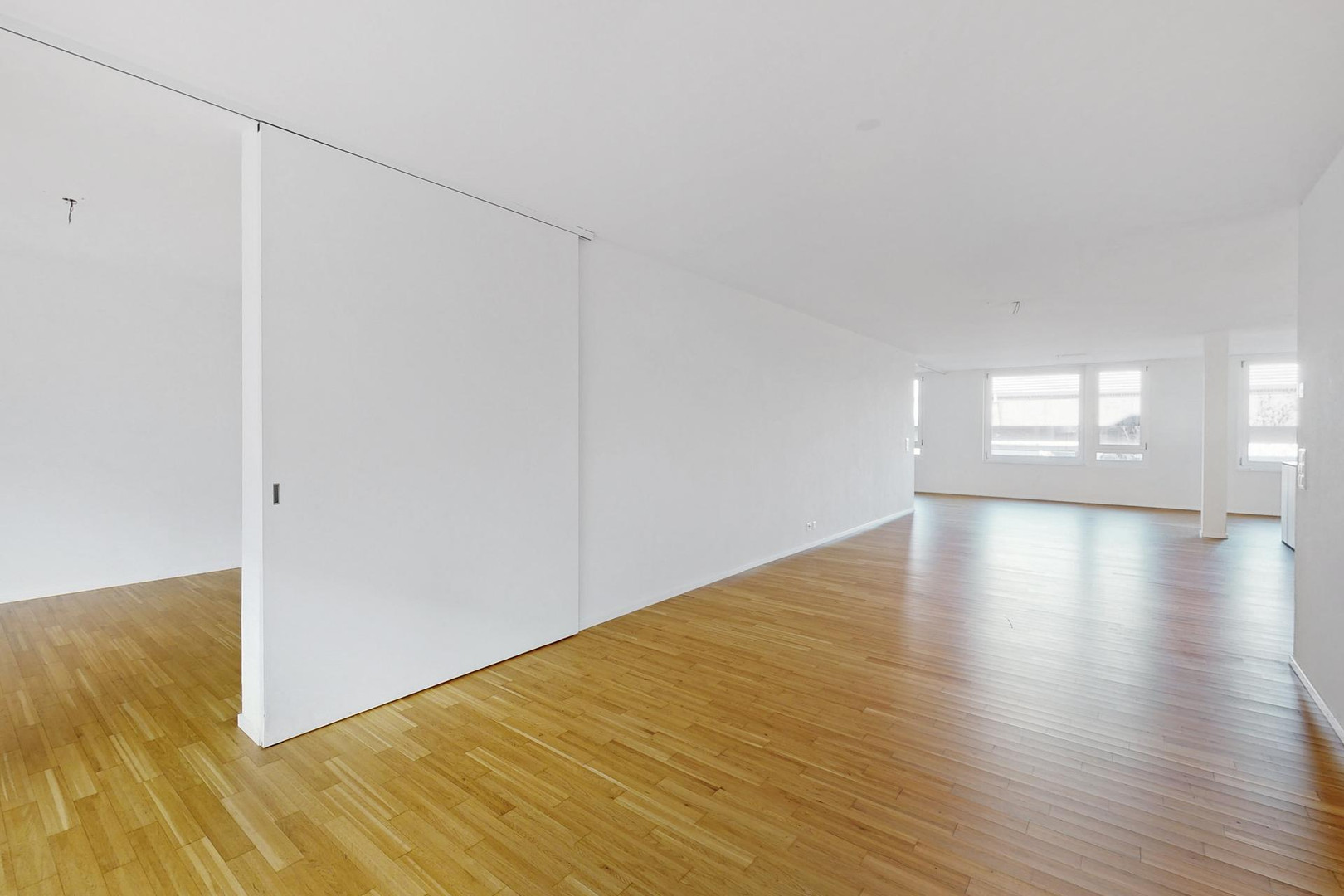 Großer leerer Wohnraum mit Holzboden