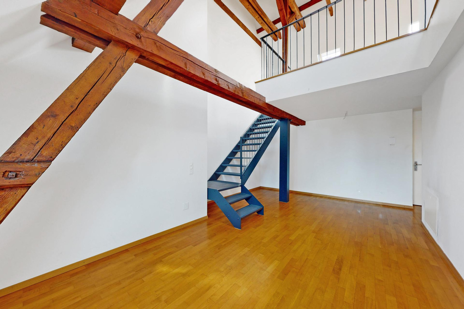 Wohnraum mit sichtbaren Holzbalken und Galerie