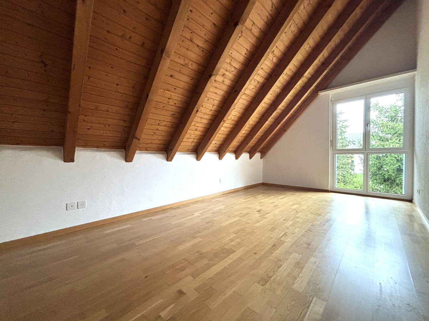 Dachgeschosszimmer mit Holzbalken und Parkett