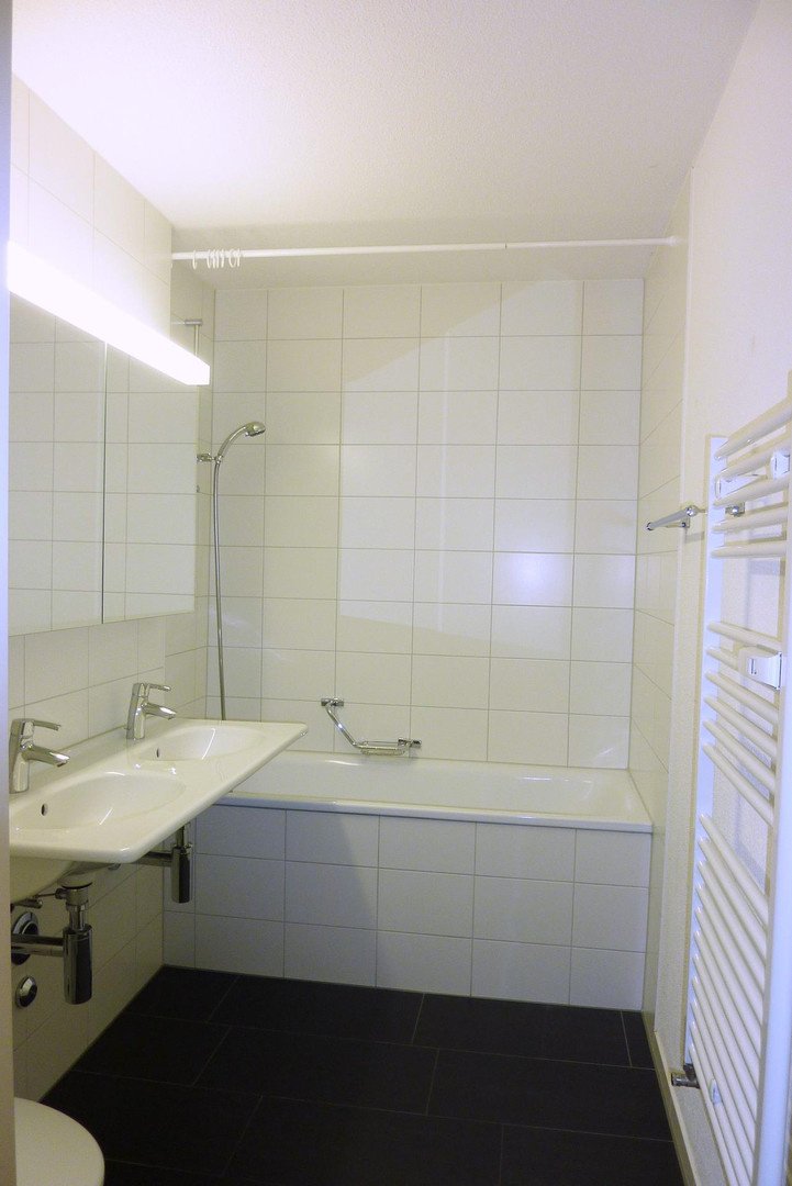 Kleines weißes Badezimmer mit Wanne und Doppelwaschbecken