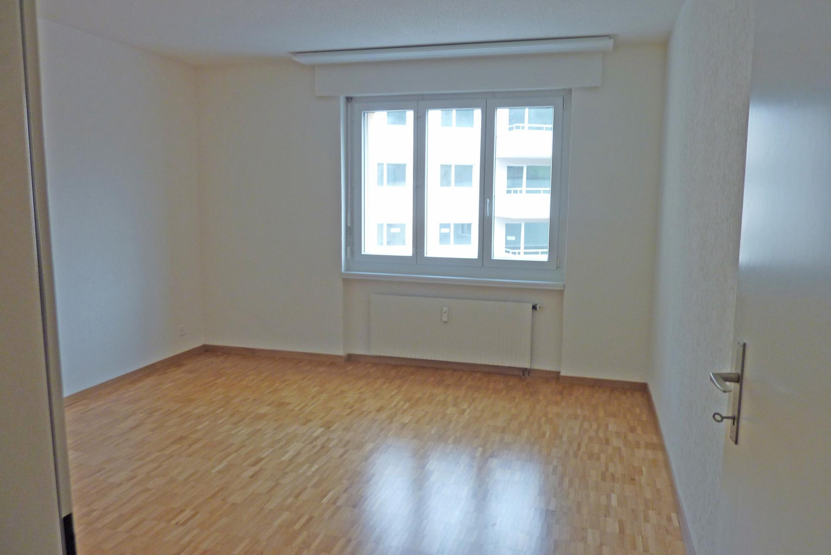 Leerer heller Raum mit Fenster und Parkettboden