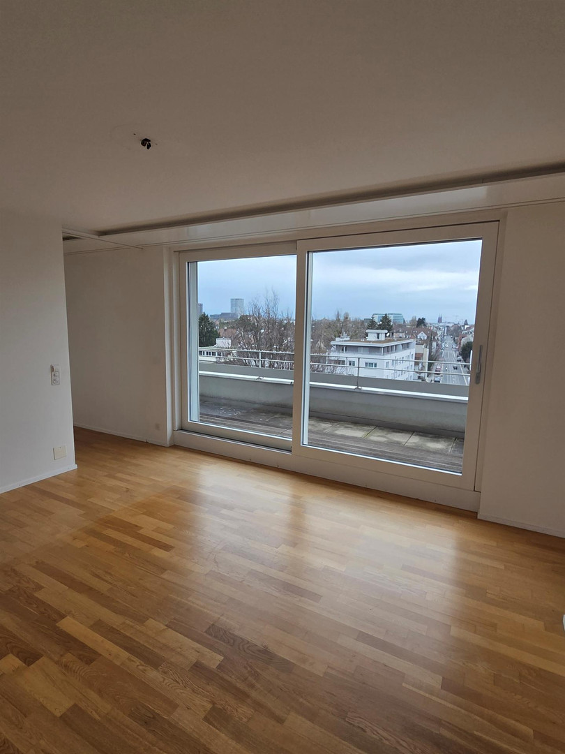 Leerer Wohnraum mit Balkon und Stadtblick