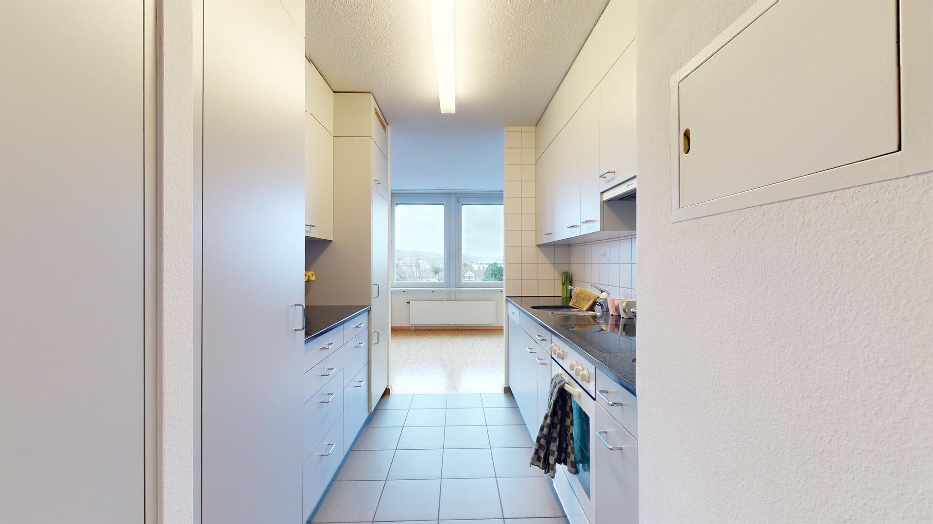 Helle, schmale Küche mit Blick ins angrenzende Zimmer