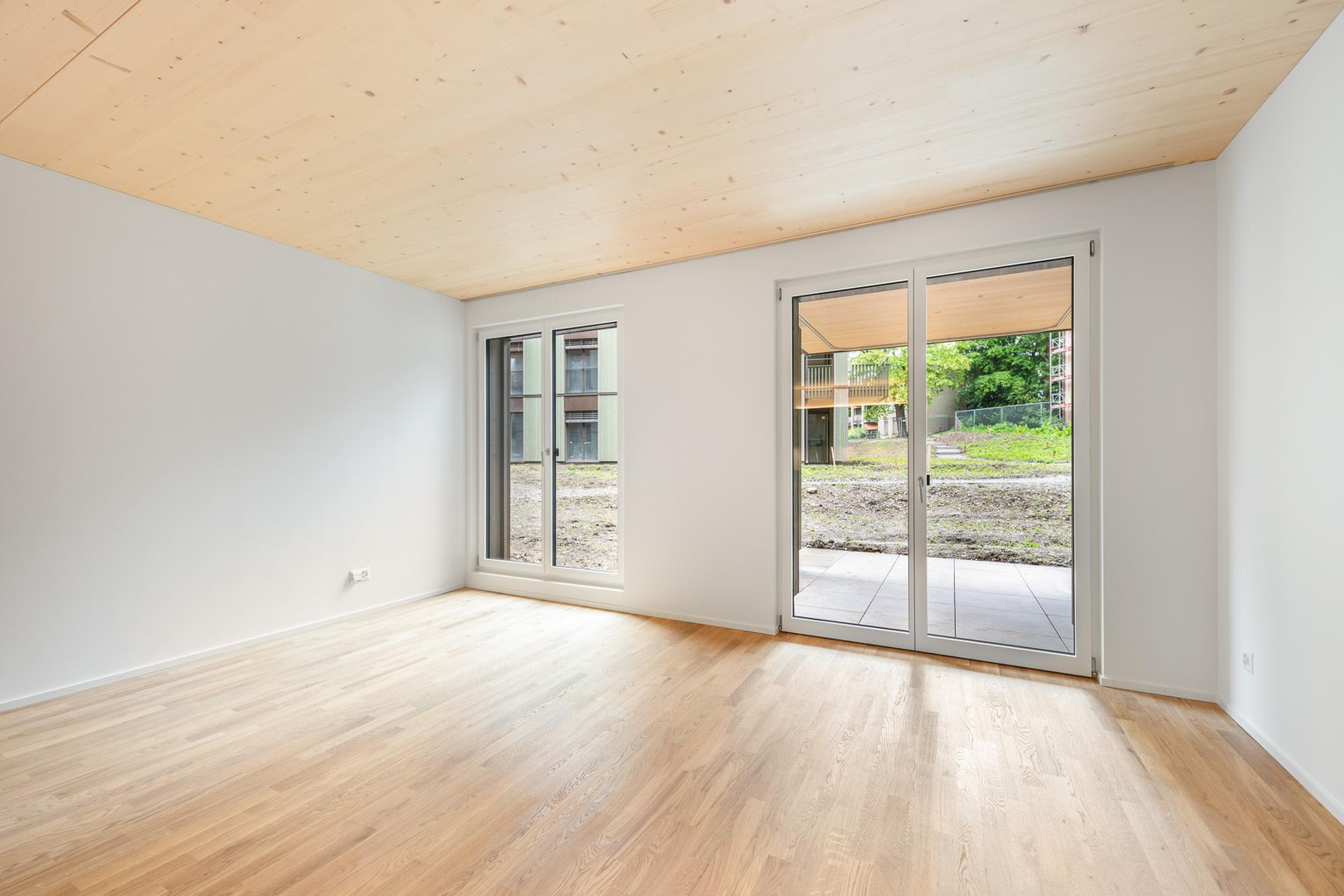Heller leerer Wohnraum mit Holzdecke und Terrassenzugang