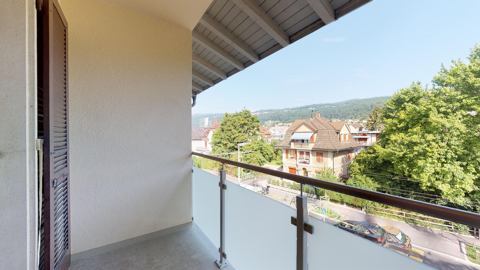 Balkon mit Aussicht ins Grüne und auf Wohnhäuser