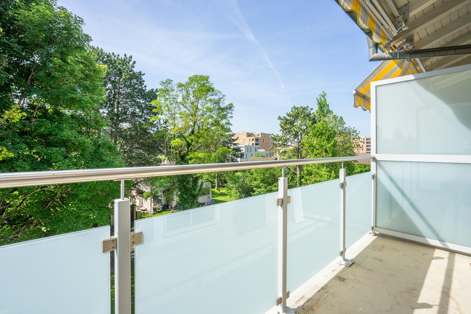 Balkon mit Glasgeländer und Grünblick