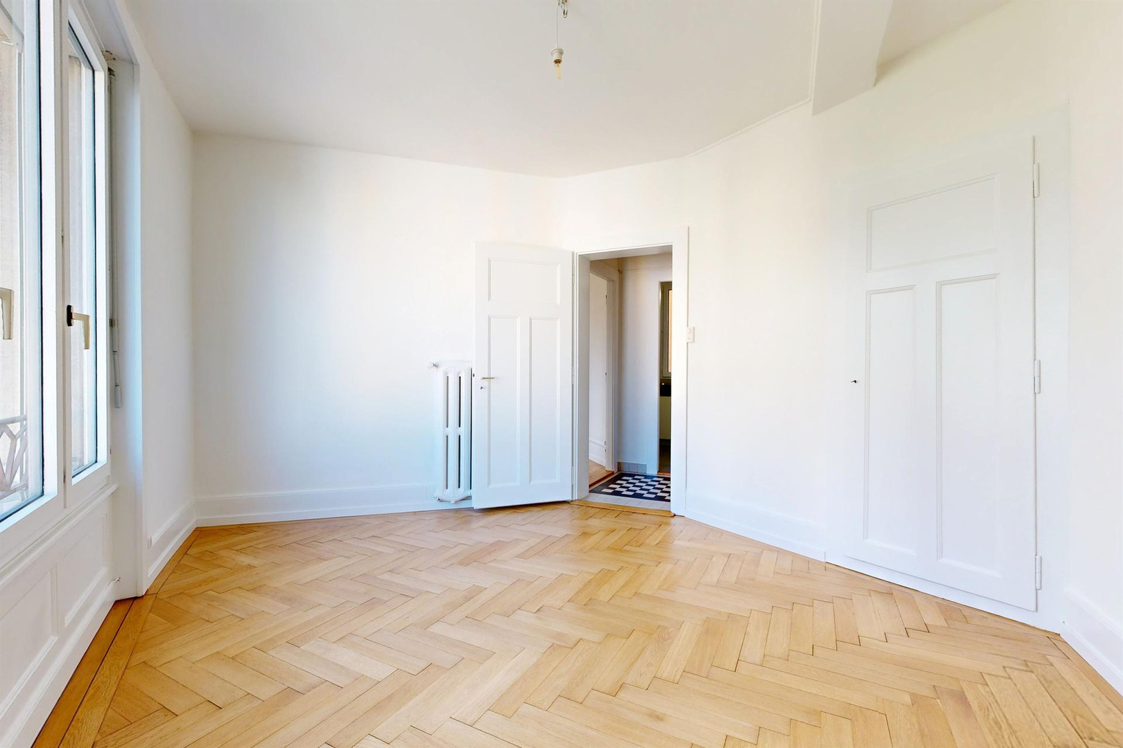 Heller, leerer Altbau-Raum mit Fischgrätparkett