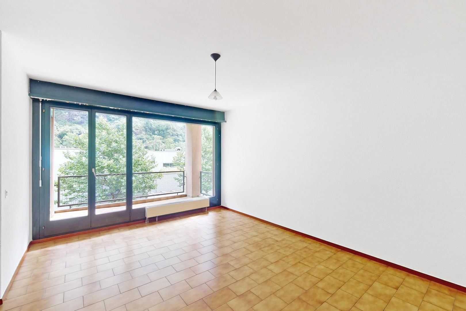 Leerer Wohnraum mit Balkonzugang