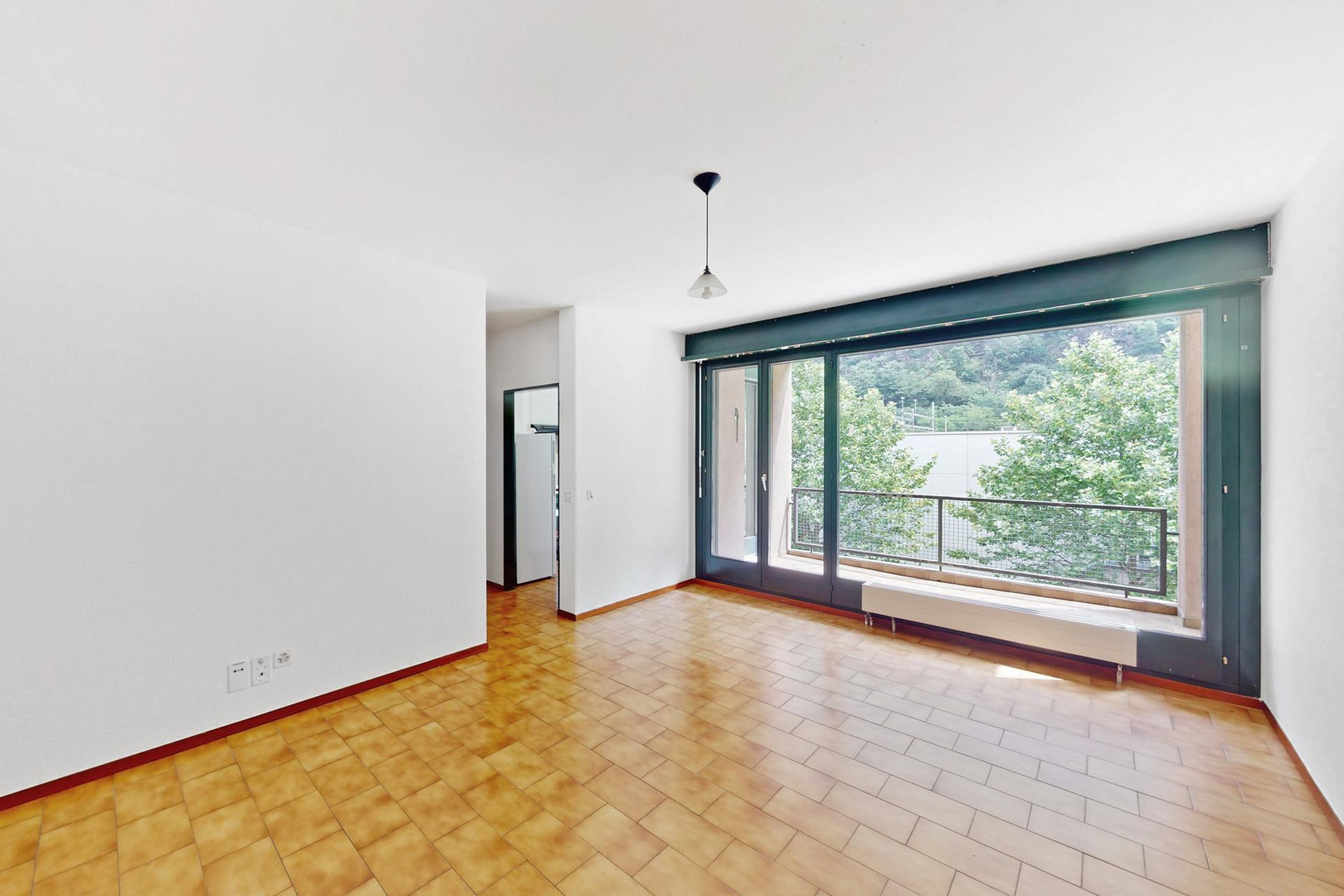Leerer Wohnraum mit großem Balkonfenster