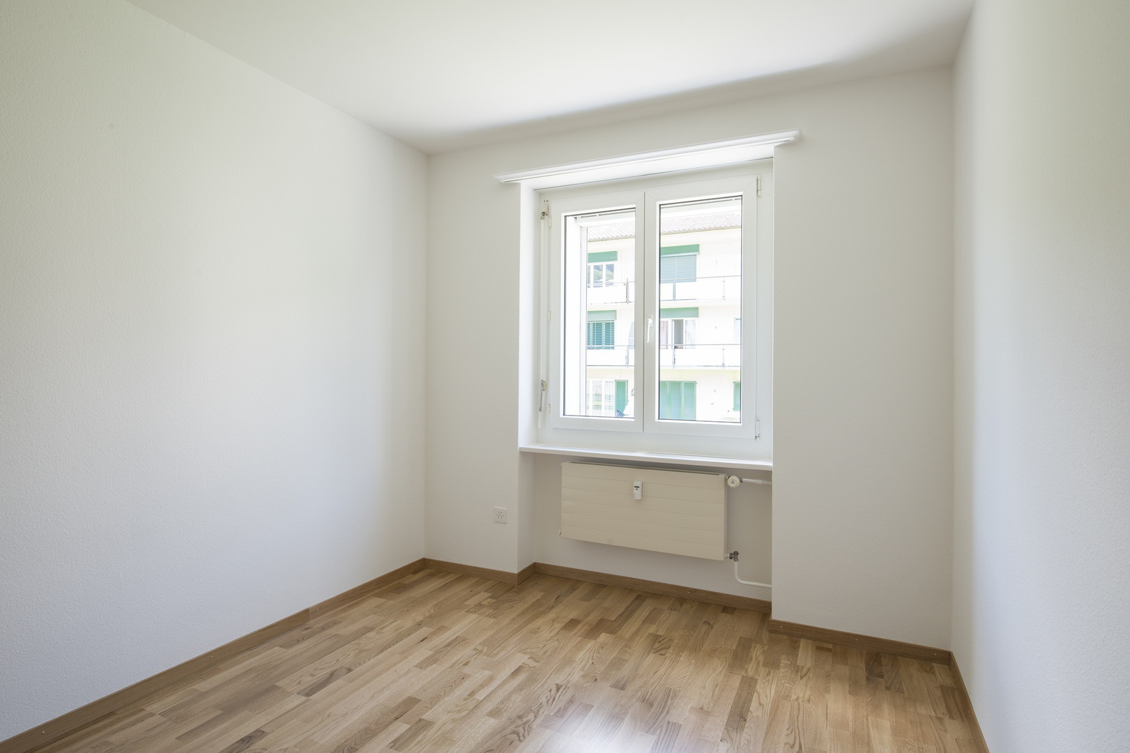 Heller leerer Wohnraum mit Fenster und Heizkörper