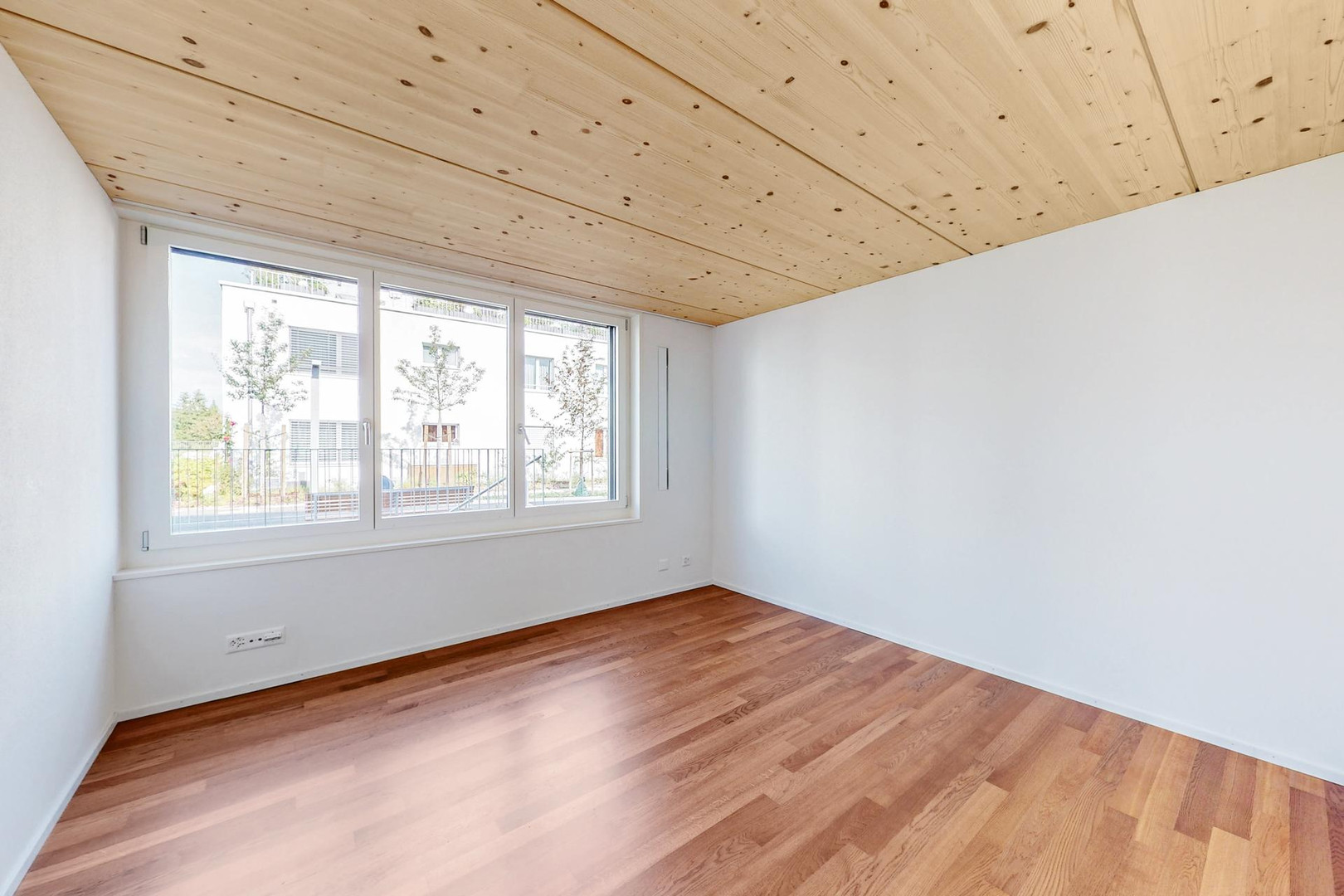 Heller leerer Wohnraum mit Holzdecke und Parkettboden