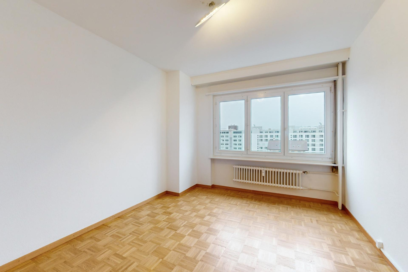 Helles, leeres Zimmer mit Fenster und Heizkörper