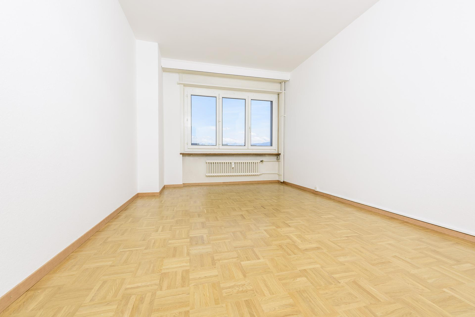 Leerer heller Raum mit Parkett und Fenster
