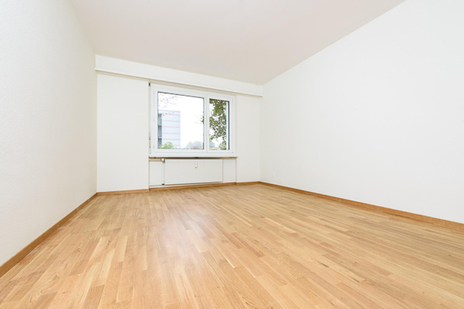 Heller leerer Raum mit Holzfußboden und Fenster