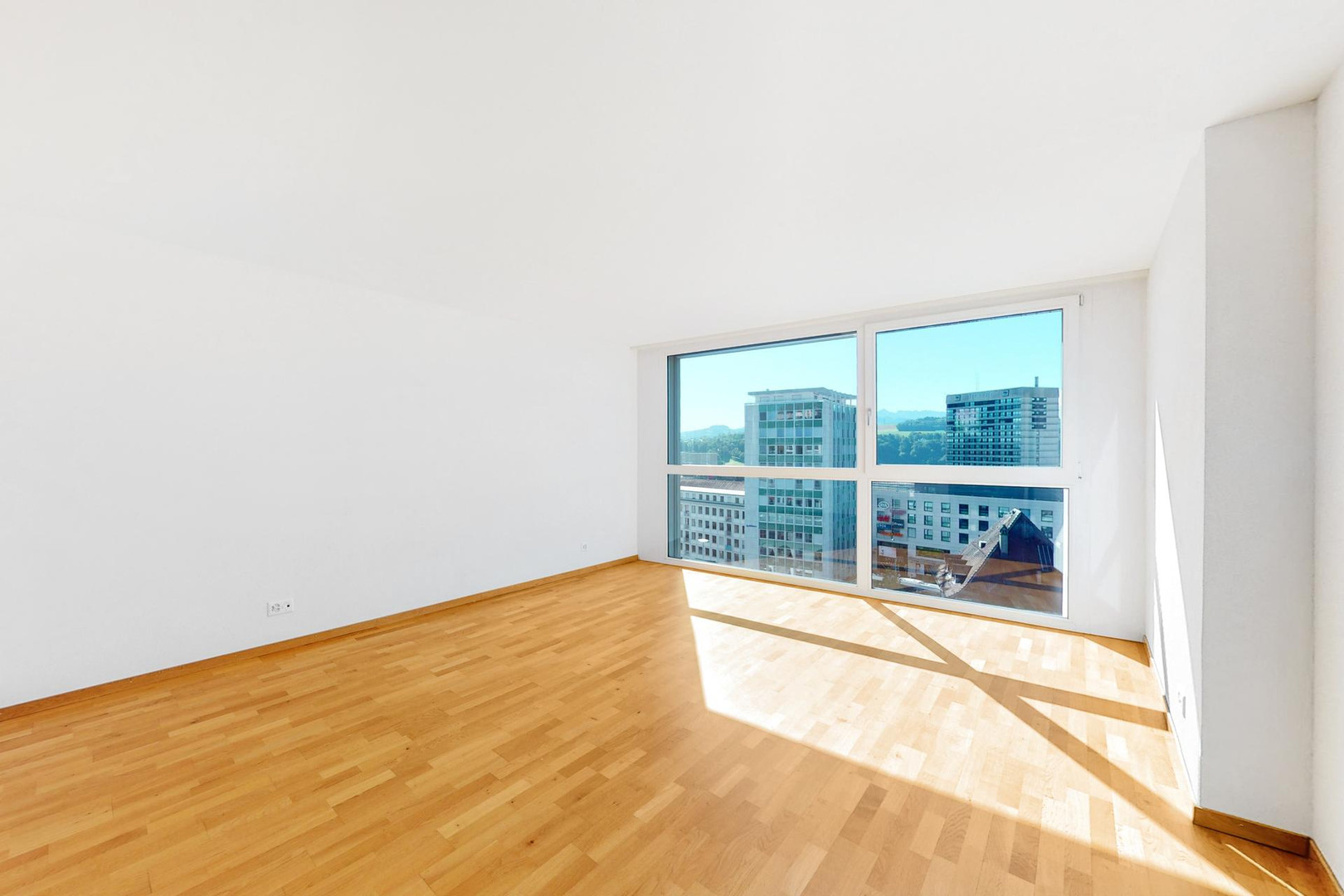 Helles, leeres Zimmer mit großem Fenster und Stadtblick