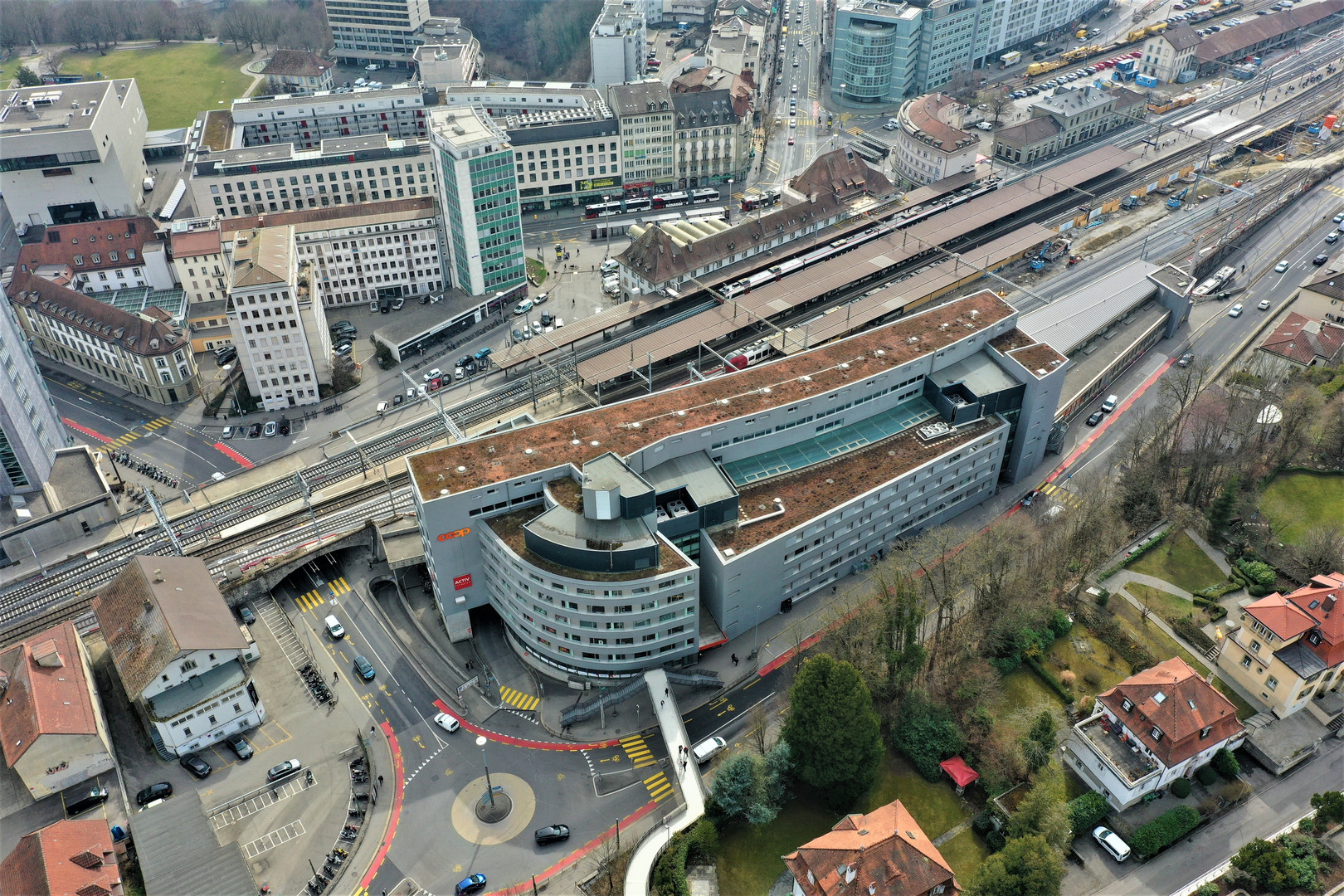 Luftaufnahme eines städtischen Bahnhofsareals mit Parkanlagen